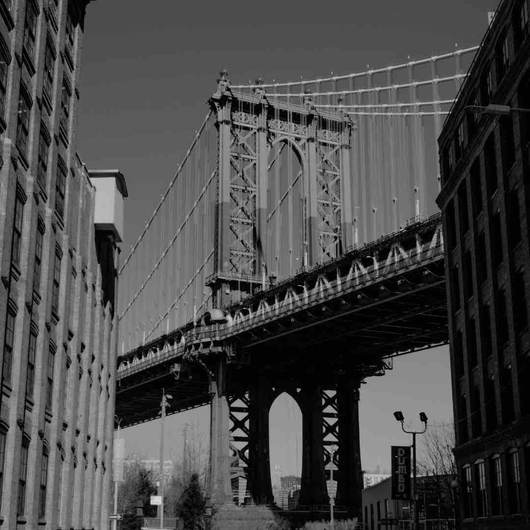 Looking up at the towering structure of the Brooklyn Bridge against a clear sky.