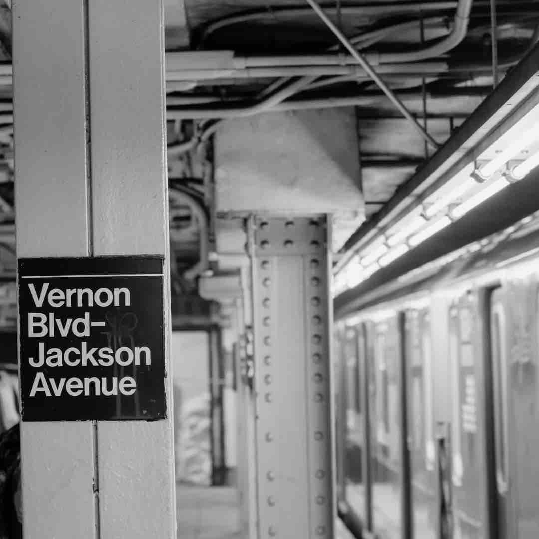 Empty subway station in Queens, NYC, with dim lighting and deserted platforms.