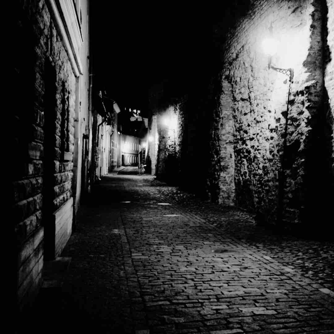 Dimly lit urban alleyway at night, enhancing a spooky atmosphere during a city ghost tour.