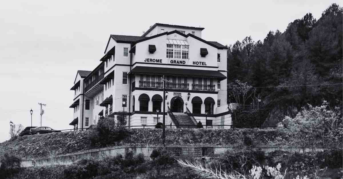 An ominous silhouette of Jerome Grand Hotel against a dark, misty sky, evoking a chilling atmosphere of mystery and intrigue.