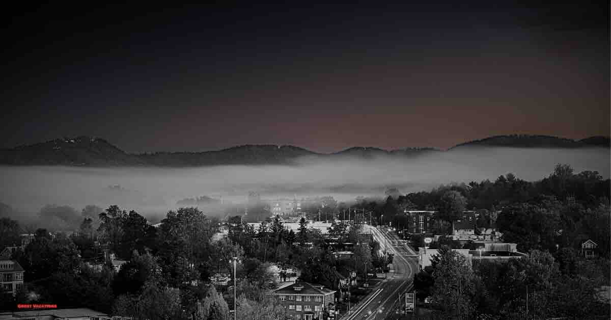 Asheville skyline at dusk with a backdrop of the Blue Ridge Mountains. Discover the city's mysterious side by exploring haunted hotels in Asheville, rich in history and ghostly legends.