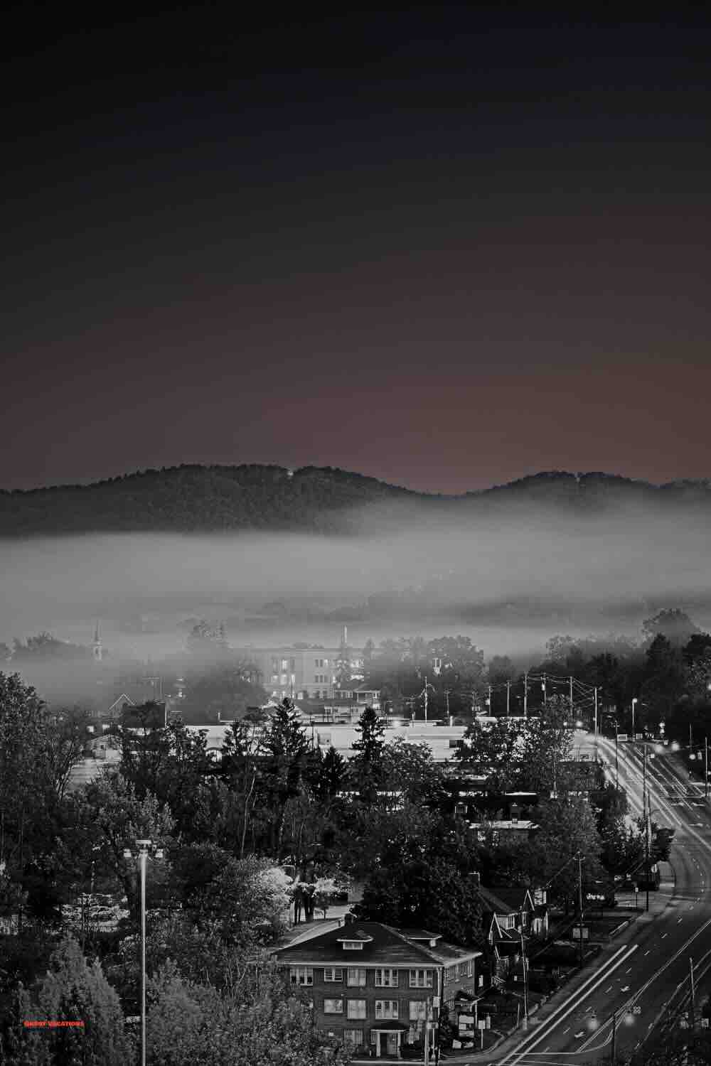 Asheville's skyline against a twilight sky, nestled in the Blue Ridge Mountains. Dive into the city's eerie past by visiting haunted hotels in Asheville, where history and hauntings await.