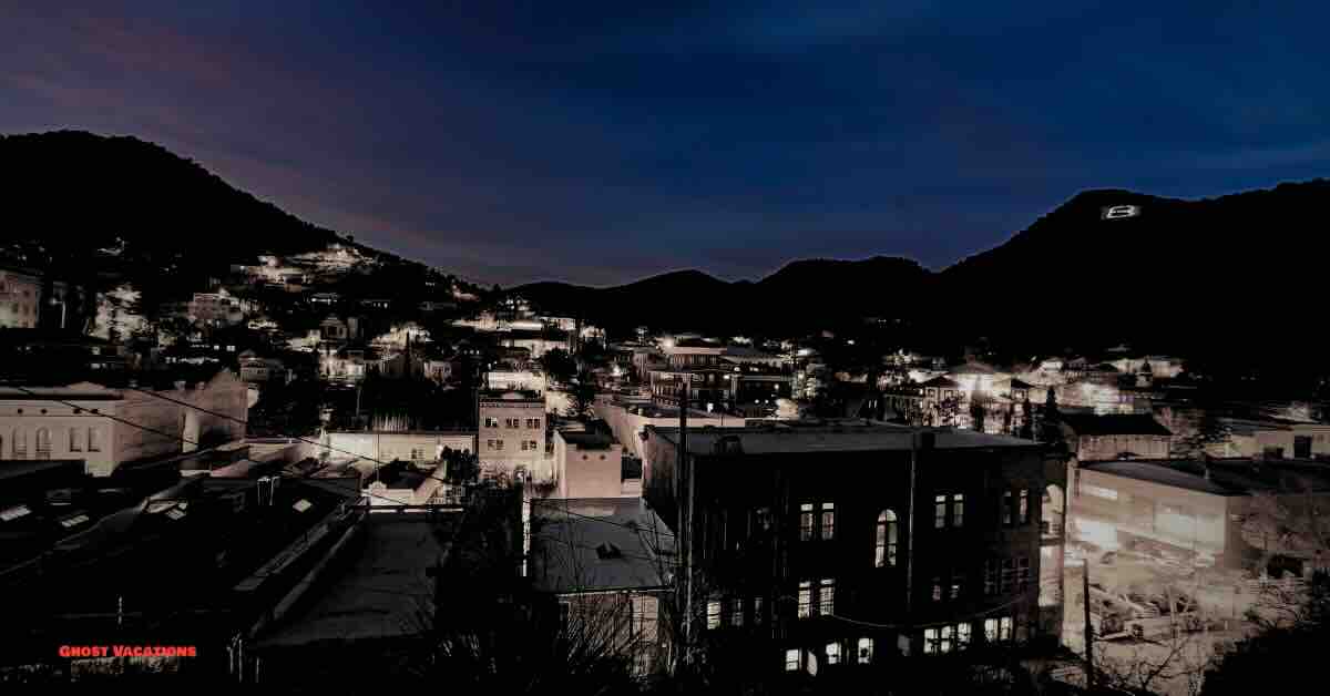 A spooky night scene in Bisbee, Arizona, showcasing the eerie allure of haunted hotels in Bisbee Arizona with historic buildings illuminated under a ghostly moonlit sky.