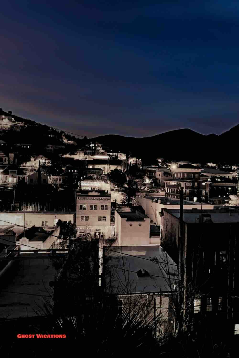 A nighttime view of Bisbee, Arizona, featuring the haunted hotels in Bisbee Arizona with their historic architecture glowing under a mysterious, moonlit sky.